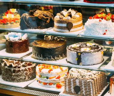 Glass bakery display case with 3 shelves of various cakes